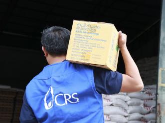 A man with a CRS vest carries a box on his shoulder