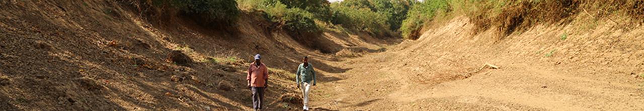 Two men walk the middle of a dry river bed in Somalia.