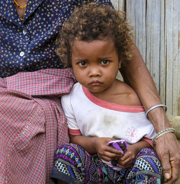 A girl sits in front of her home