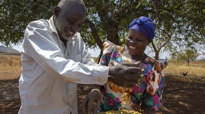 Uganda woman and man with a bowl of grain 