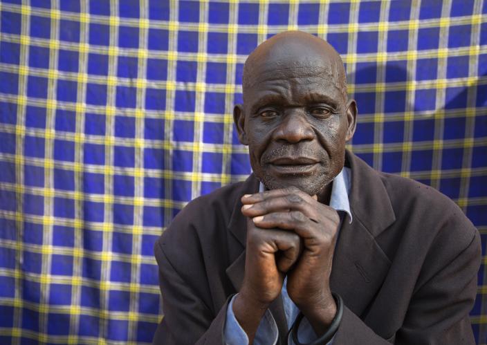 A man sitting in front of a blue fabric.