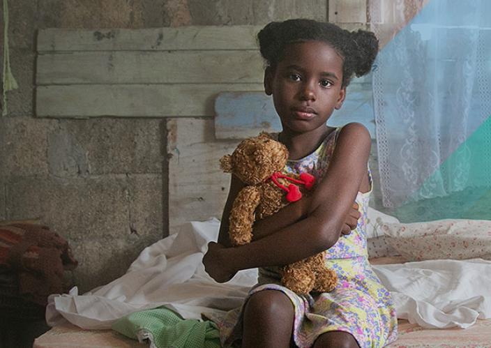 seated young girl holding a yellow teddy bear