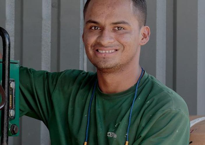 young man in green shirt working with green machine with tubing
