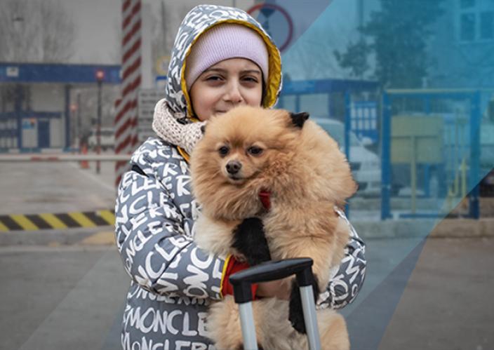 young girl with winter coat holding small, tan fluffy dog