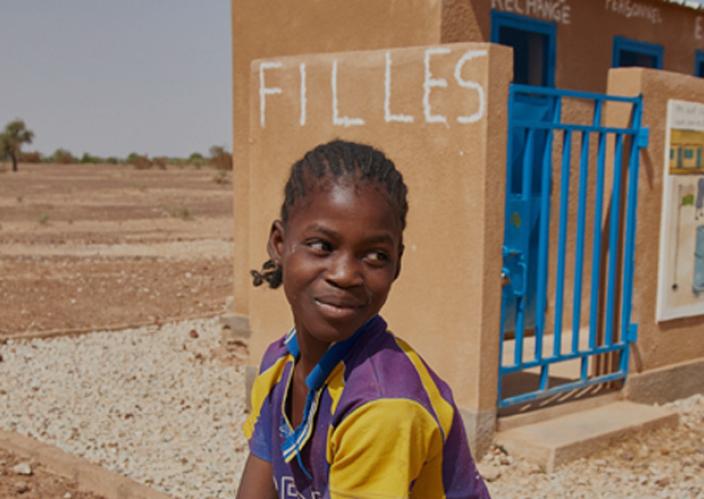 A young girl in front of a building.