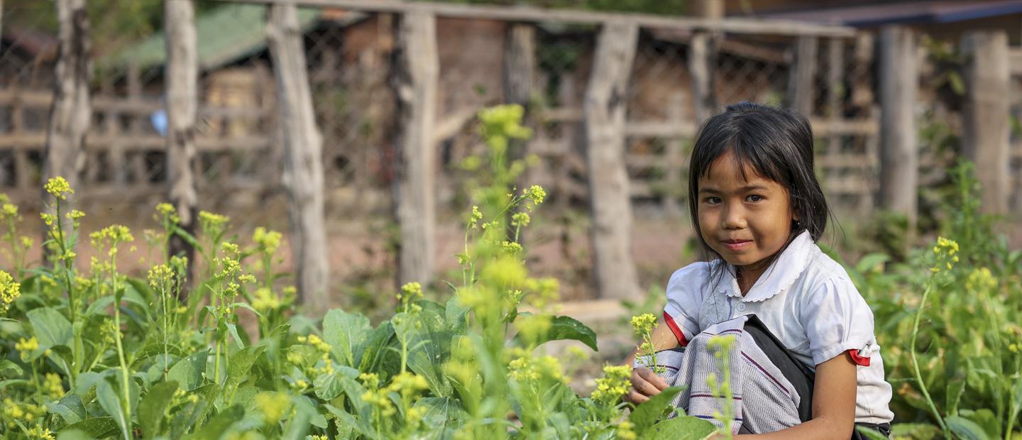 A young girl sitting by flowers.