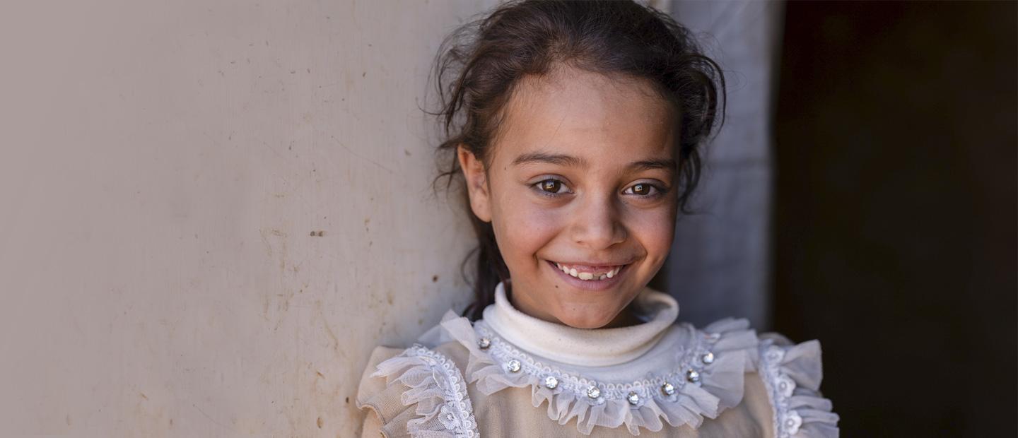 A young girl standing in front of a wall.