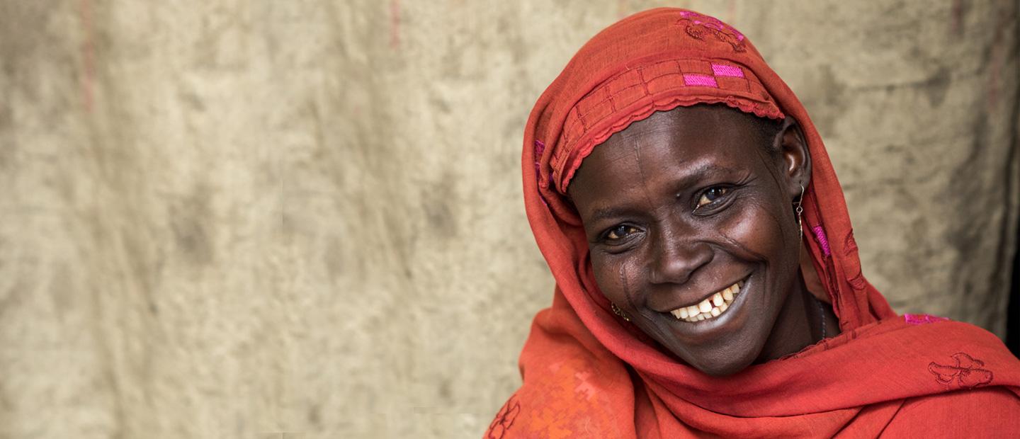 A woman in red head scarf smiling.
