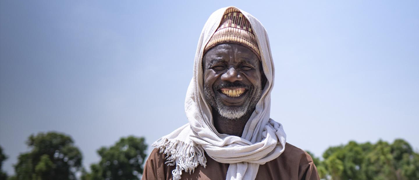A man in traditional clothes, smiling.