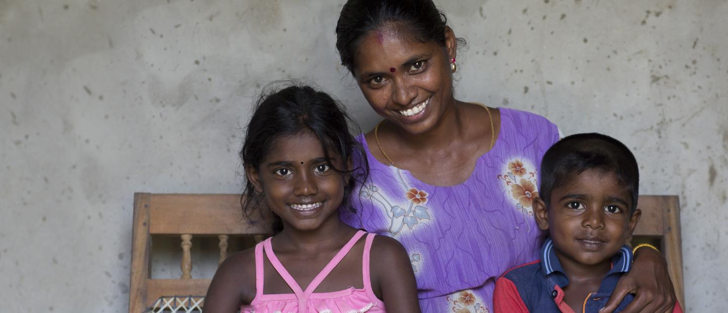 A woman and 2 children sitting on a bench.
