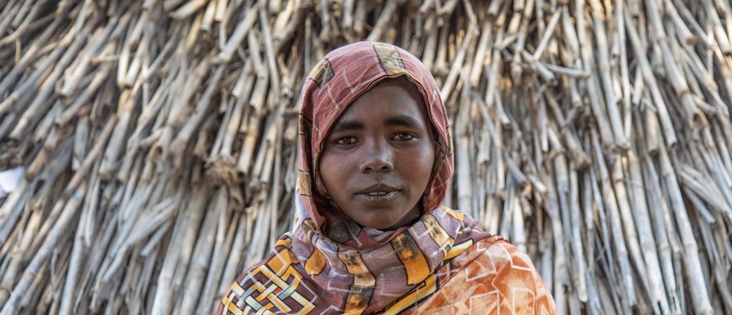 A woman in front of a hut.