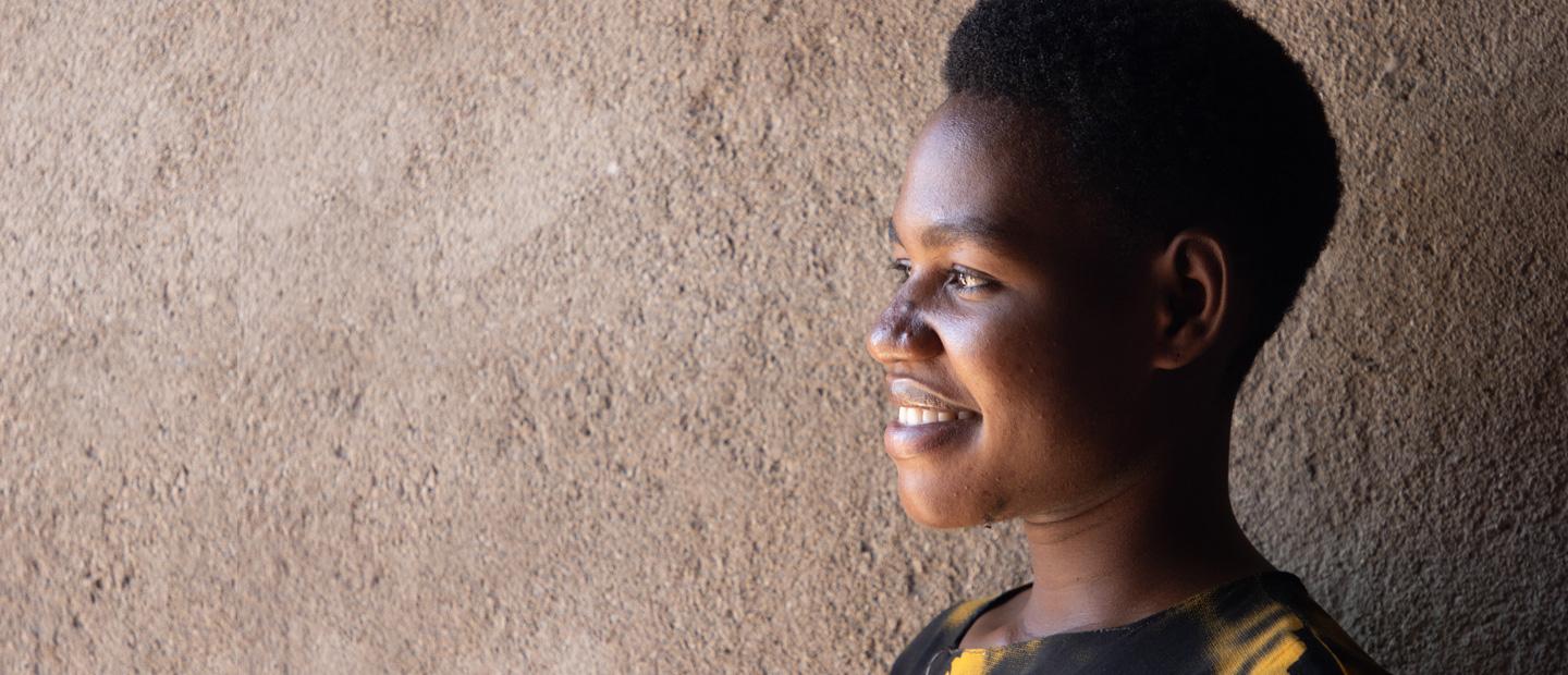 A woman standing by a wall.