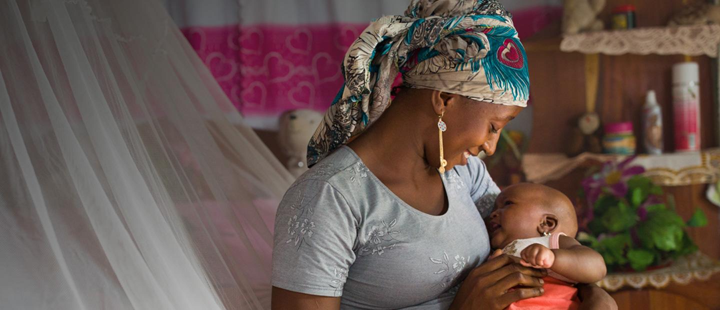 A woman sitting on a bed holding a baby.