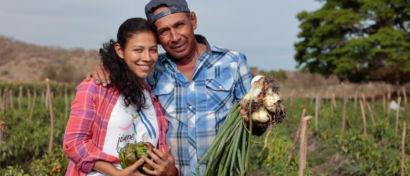 Father and daughter holding their harvest.