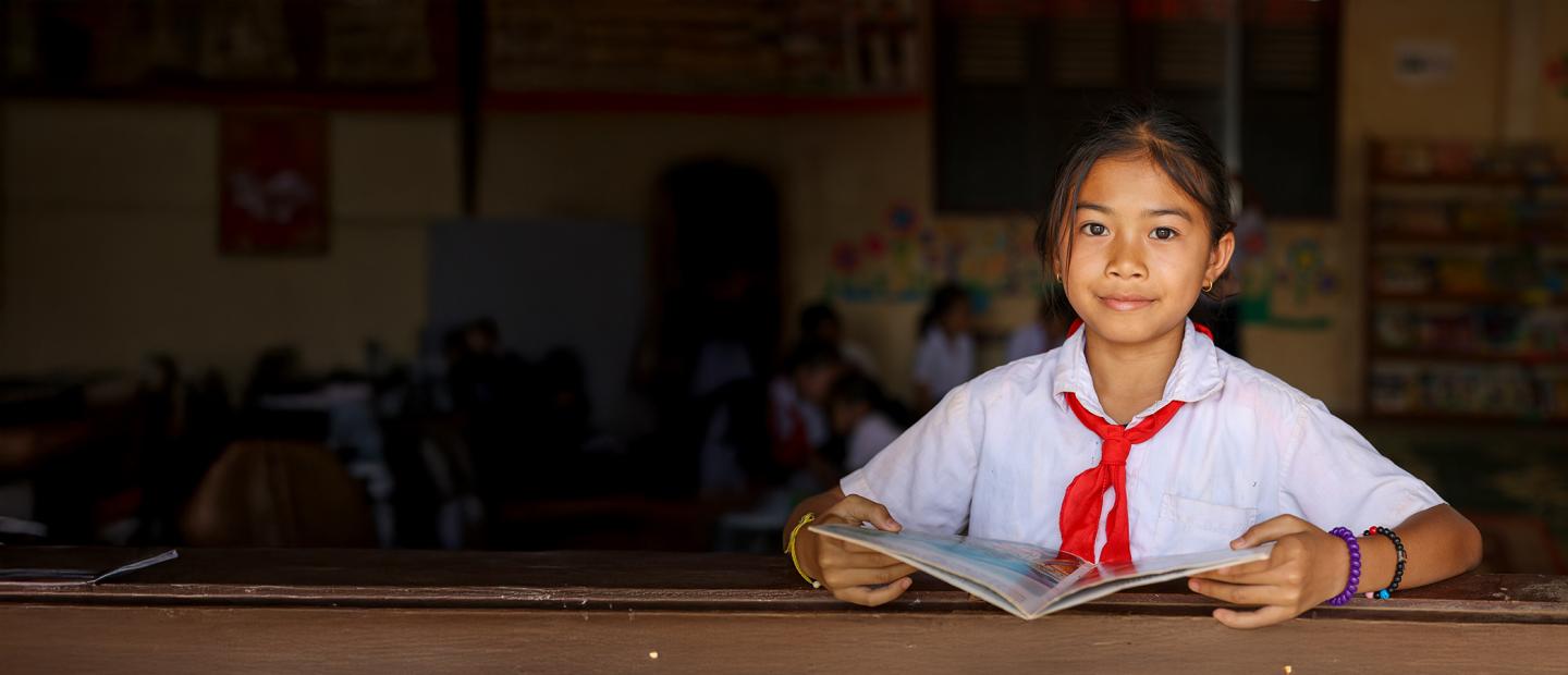 girl in school posing for portrait with a book
