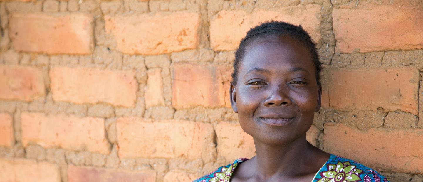 A woman standing before a brick wall.