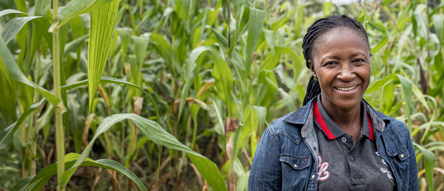 A woman standing before a corn field.