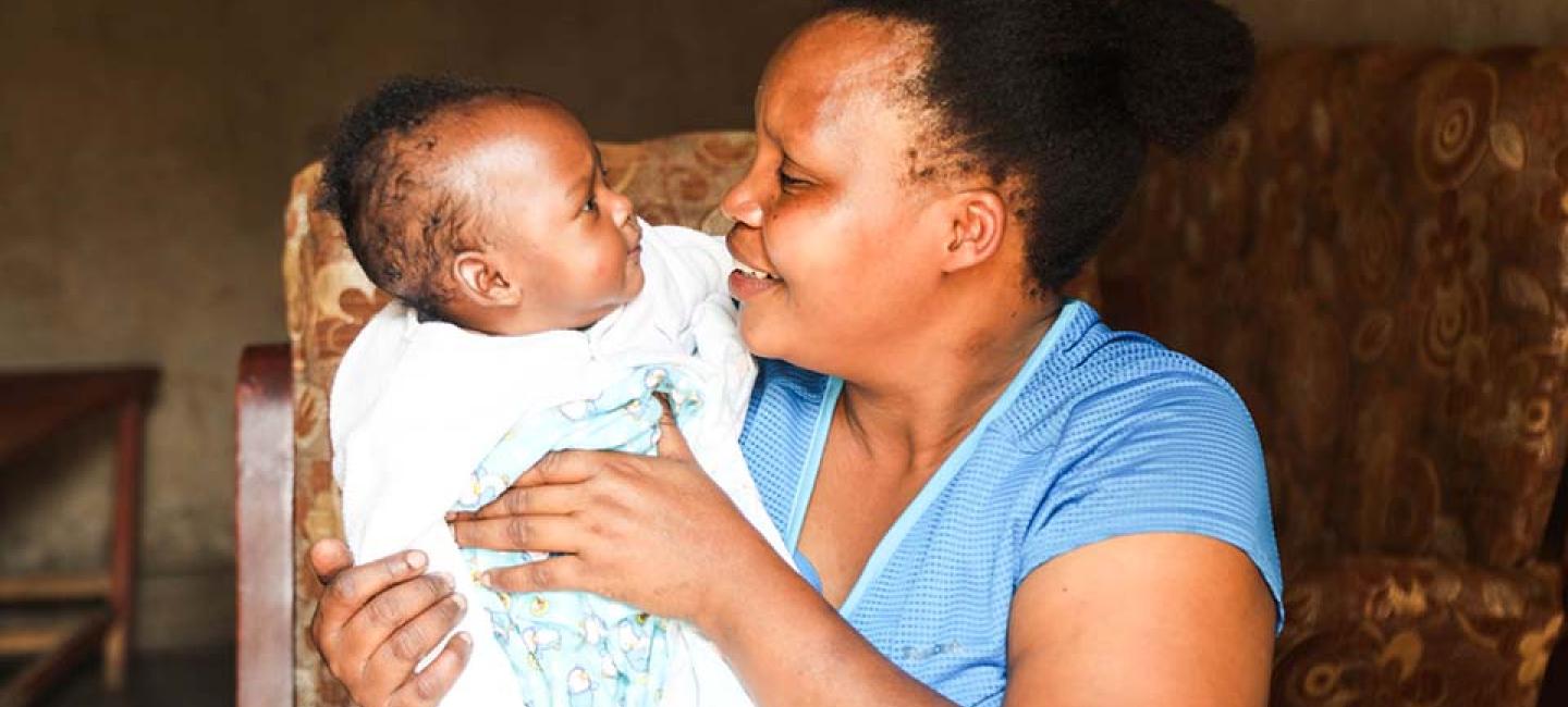 mother seated in a chair lovingly holds infant 