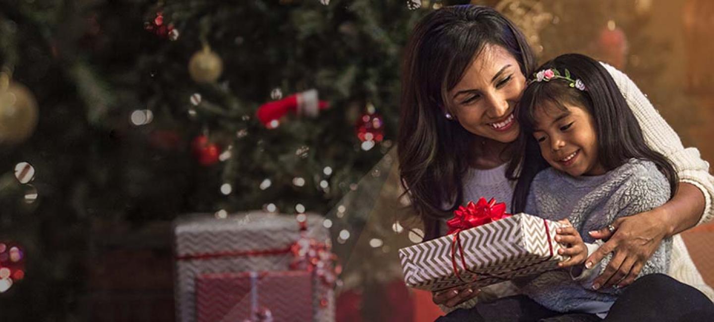 A woman and a child in front of a Christmas tree.