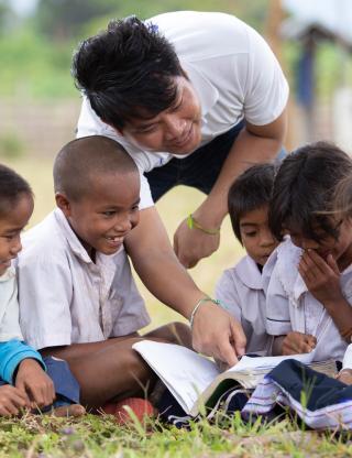 man teaching several young kids to read