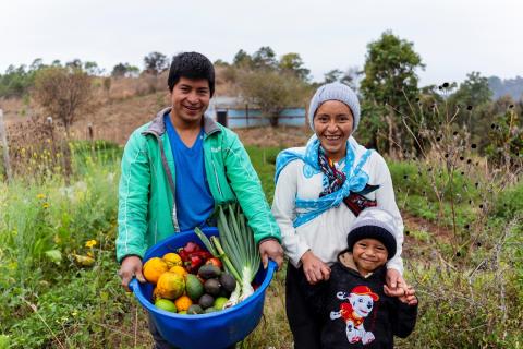 2 farmers with son show off their basket of harvested produce