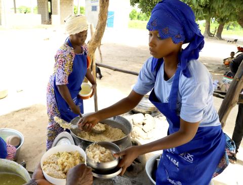 Fatimatou Ousmane works busily behind pots in an open-air kitchen
