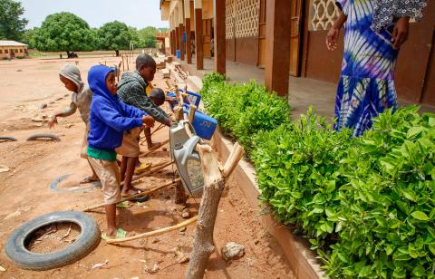 Students wash their hands outside their school.