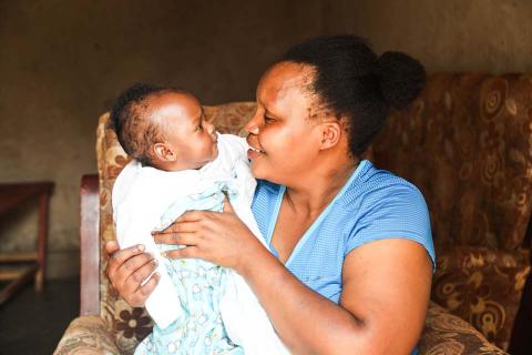 mother seated in a chair lovingly holds infant