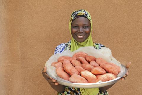 Benin woman displaying large shallow bowl of soy cheese