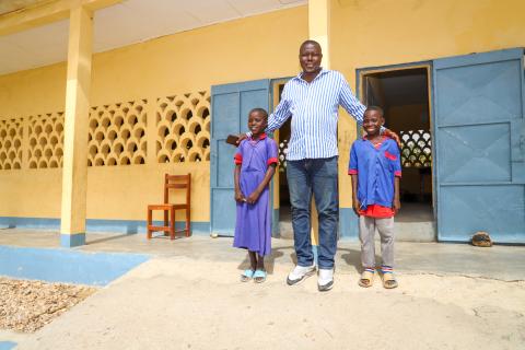 teacher stands with students at school in Cameroon