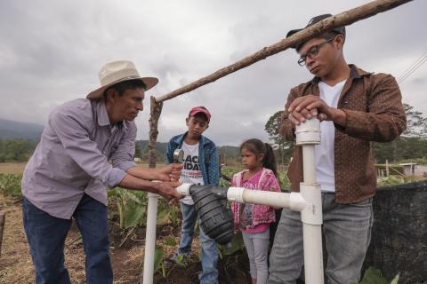 Nery and three of his children examine a drip irrigation system