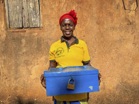 A woman holds her savings group's lock box.