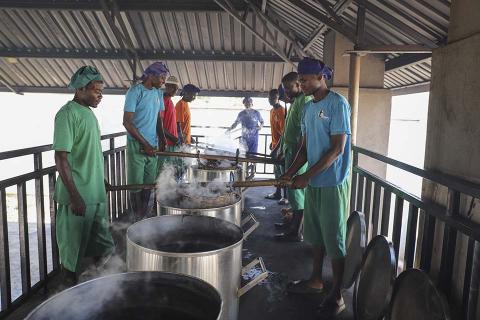 Men standing around boiling pots.