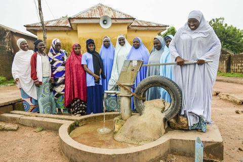 Women standing around a water pump.