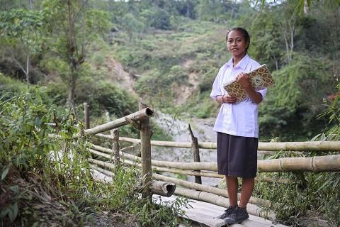 A girl stands on a bridge.