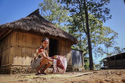 A girl in front of a hut.