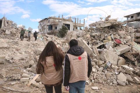 Caritas staff in front of rubble.