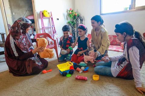 A woman and children sitting on the floor.