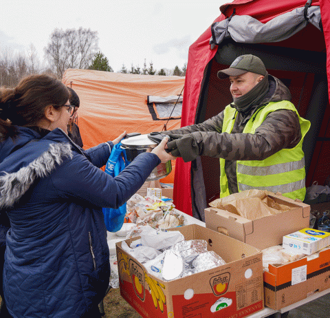 gif flipping from black and white photo to color of people handing out food