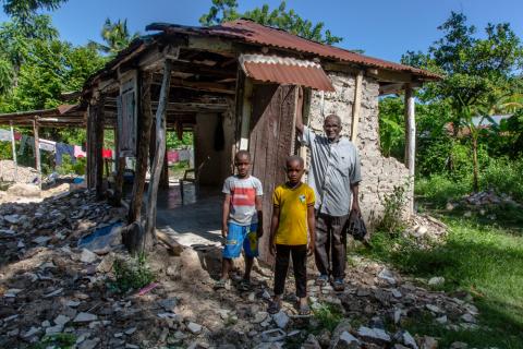 A man and two children around rubble.
