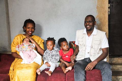 Mother holding infant sits with 2 toddlers and her husband.