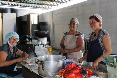 3 mujeres cocinan en una cocina preparando una comida