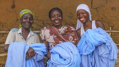 3 women holding blue fabric.