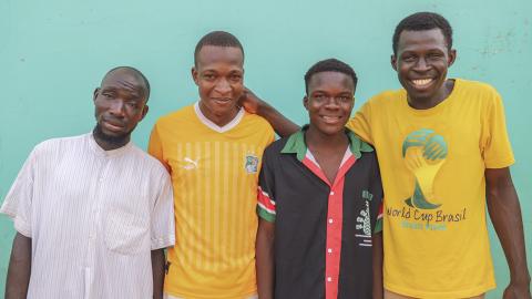 4 men in front of a green wall.