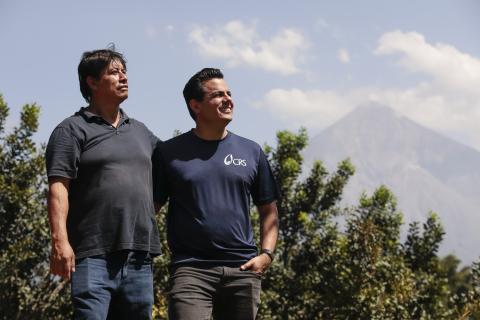 two men standing outside with mountain in the background