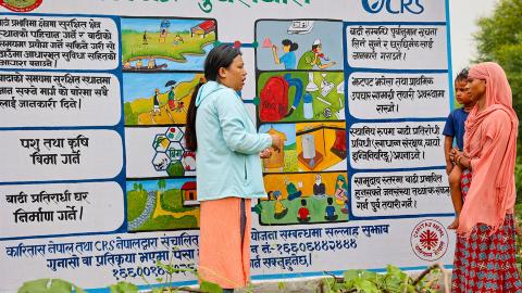 Women talking in front of a banner.