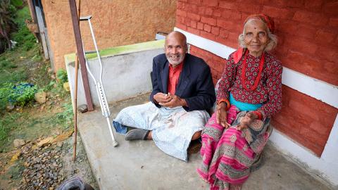 Elderly people sitting in front of a building.