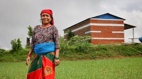 A woman in red head scarf standing in a field.