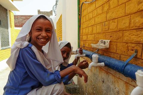 2 young girls washing their hands.