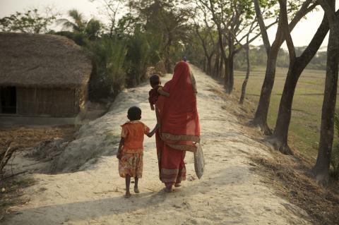 woman holding a baby and walking with girl